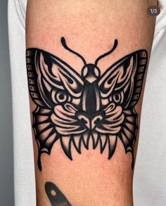 a black and white photo of a butterfly tattoo on the arm, with an image of a cat's face