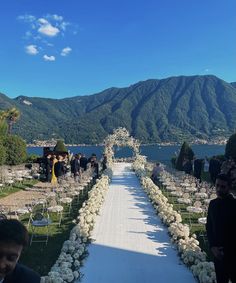 an outdoor wedding setup with white flowers and greenery on the aisle leading to mountains