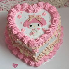 a cake shaped like a heart with a hello kitty face on the top and pink icing