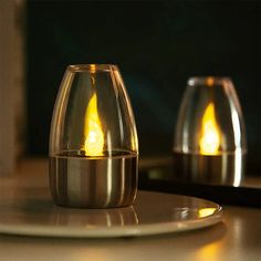 two lit candles sitting on top of a white plate