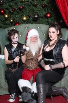 three people dressed as santa claus sitting on a couch