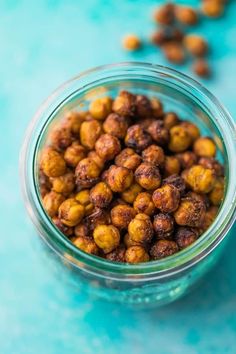 a glass jar filled with chickpeas on top of a blue table