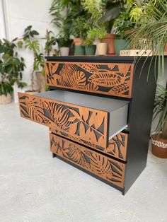 the drawers are made out of wood and have intricate designs on them, as well as plants