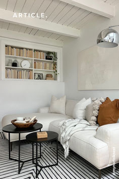 a living room with white couches and bookshelves on the wall above them