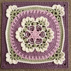 a crocheted square is shown on the floor in purple, green and white