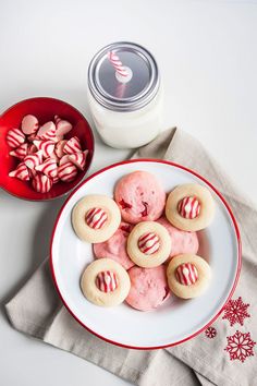 a white plate topped with cookies next to a red bowl filled with candy canes