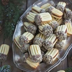 a glass plate filled with cookies on top of a wooden table next to pine cones