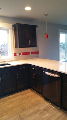 an empty kitchen with black cabinets and white counter tops