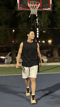 a man standing on top of a tennis court next to a basketball hoop at night