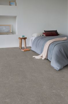 a bed sitting on top of a floor next to a white wall with a window