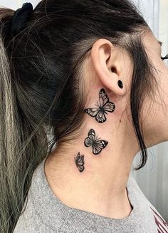 a woman's neck with three butterflies tattoo on her left side behind the ear