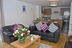 a living room with two couches and a table in front of the kitchen area