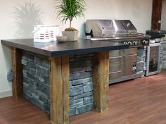 an outdoor kitchen with grill, sink and potted plant on the counter top in front of it