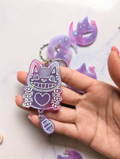 a person holding a keychain with a cat design on it's face