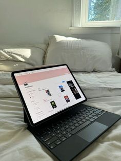 an open laptop computer sitting on top of a bed next to pillows and pillow cases