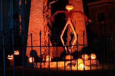 halloween pumpkins lit up in front of a house with carved jack o lantern faces