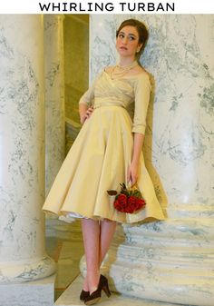 a woman in a short dress standing next to columns and holding a bouquet of flowers