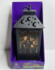 a purple box with a black lantern in it's center and the words happy halloween written on it