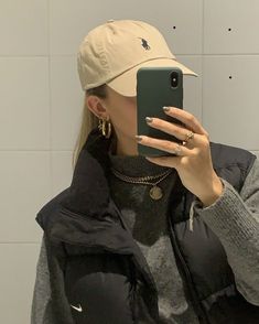 a woman taking a selfie in front of a mirror wearing a hat and jacket