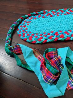 two pieces of fabric sitting on top of a wooden floor next to a rug and bag