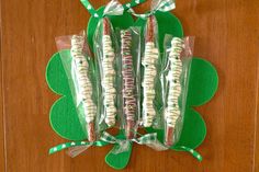 four candy sticks wrapped in cellophane and tied with green ribbon on top of a wooden table