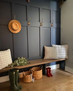 a wooden bench sitting in front of a wall with two hats on top of it