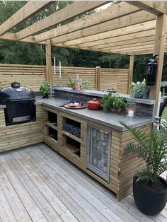 an outdoor kitchen with grill, sink and potted plants on the counter top area