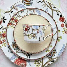 an ornately decorated tea cup and saucer set on a floral patterned plate with matching plates