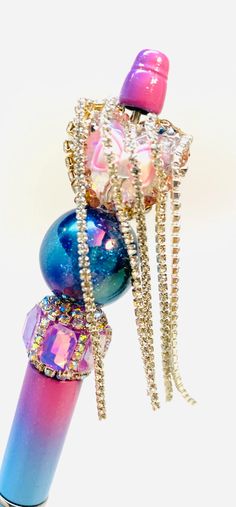 a pink, blue and purple object with chains hanging off of it's end