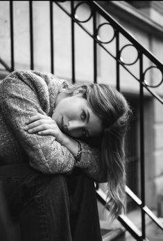 black and white photograph of a woman leaning on the stairs with her head resting on her hands