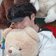 a young man holding a teddy bear in front of several stuffed animals on display at a store