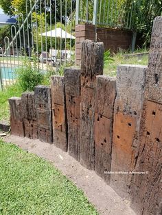 several pieces of wood are stacked on top of each other in the grass next to a pool