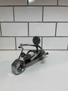 a small metal motorcycle on a white counter top next to a tile backsplash