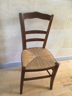 a wooden chair sitting on top of a hard wood floor next to a white wall