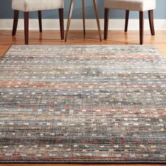 two chairs sitting next to each other in front of a rug on top of a wooden floor