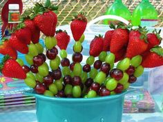 grapes and strawberries are arranged in a blue bowl on a table with other items