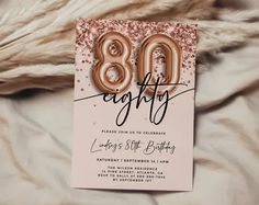 an 80th birthday party card with balloons and confetti on the front, sitting on a bed