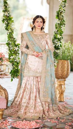 a woman in a pink and blue lehenga with floral decorations on the side