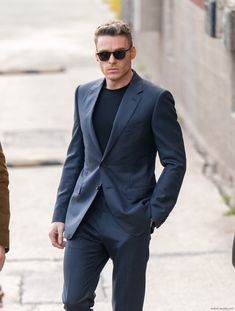 a man in a suit and sunglasses walking down the street