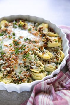 a casserole dish filled with pasta and sauce on a pink and white checkered cloth