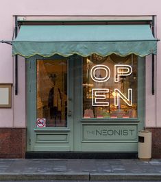 an open sign is lit up in front of a storefront with green awnings