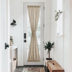 an entryway with a wooden bench, potted plant and white walls in the background