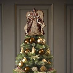 a christmas tree with gold ornaments and angel on top