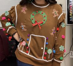 a woman wearing a gingerbread christmas sweater with candy canes on the front and green wreath on the back