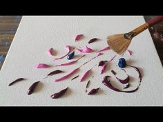 there is a paintbrush and some pink petals on the table