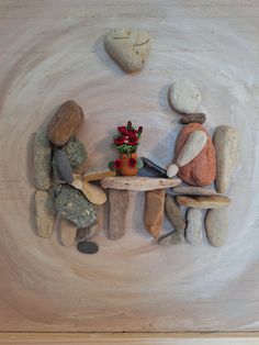 two people are sitting at a table made out of rocks and stones that look like they are holding hands