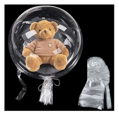 a teddy bear in a sweater sitting on top of a clear ball with a dummy behind it