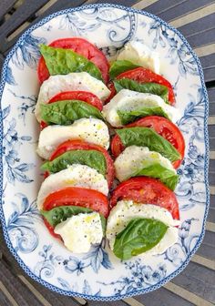 tomatoes, mozzarella and basil on a blue and white plate