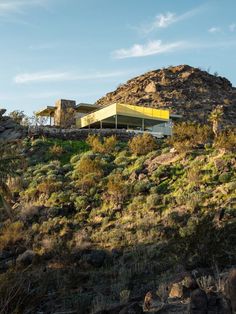 a house on top of a hill with mountains in the background