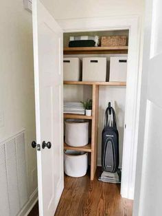 an open closet with white containers and black vacuum